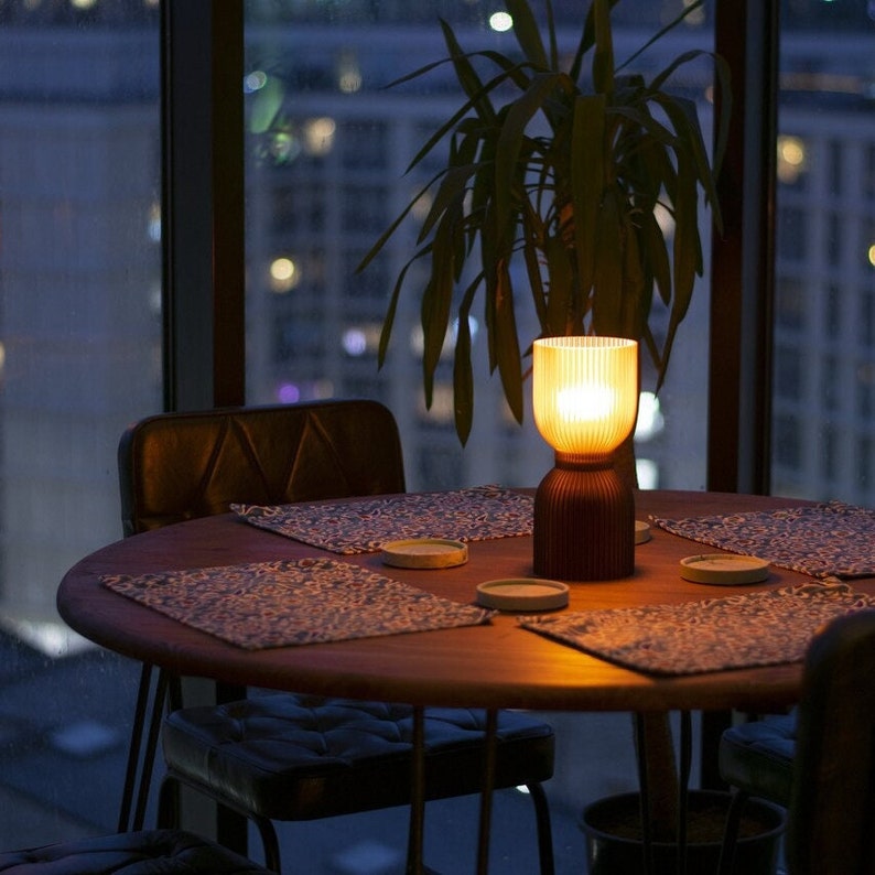 DIABOLO lamp adding warm amber glow to a modern living room. Made from recycled plastic, this eco-friendly lighting option is ideal for Scandinavian or boho-style decor. Adds cozy ambient lighting for a welcoming home atmosphere.