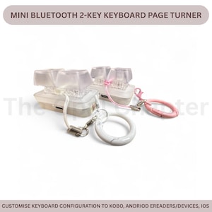May include: Mini Bluetooth 2-key keyboard page turner. The device has a clear, rectangular base with two transparent keycaps. It includes a white lanyard, a pink carabiner, and a white marble-effect ring. The text on the image says "CUSTOMISE KEYBOARD CONFIGURATION TO KOBO, ANDRIOD EREADERS/DEVICES, IOS."