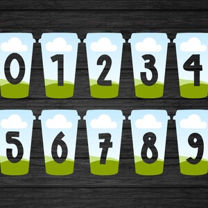 Puede incluir: Diez vasos de papel azul y blanco con hierba verde y nubes blancas impresas en ellos. Cada vaso tiene un n&uacute;mero negro impreso en &eacute;l, del 0 al 9.