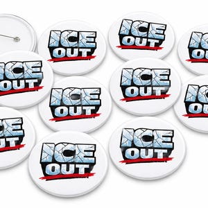 Puede incluir: Un conjunto de botones redondos blancos con las palabras "ICE OUT" en una fuente de hielo agrietado, delineadas en negro, con una barra roja debajo. Un botón tiene un alfiler en la parte posterior.