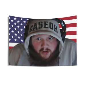 May include: A white hooded sweatshirt with the word "CASEOH" printed in black on the front. The sweatshirt is worn by a person with a beard and is partially obscured by an American flag.