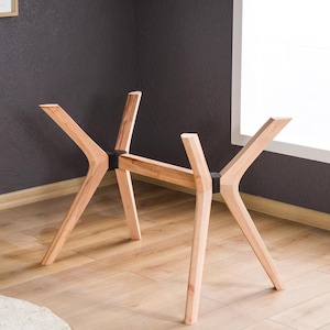 Può includere: Base per tavolo in legno dal design moderno. Presenta quattro gambe angolate che si incontrano al centro, creando una base stabile ed elegante. Il colore naturale del legno aggiunge calore ed eleganza. La base misura 100 cm di lunghezza.