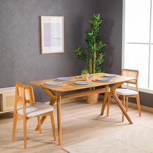 May include: A wooden dining table with a light wood finish and six chairs. The chairs have a woven cane back and a white cushion. The table is set with six place settings, each with a blue and white patterned plate.