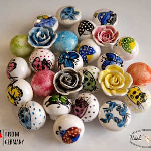 Peut inclure: Un ensemble de 20 boutons en céramique peints à la main avec différents motifs, notamment des papillons, des chats, des fleurs et des pois. Les boutons sont tous blancs avec des accents colorés et mesurent environ 3,8 cm de diamètre.  De l'Allemagne.