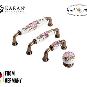 Puede incluir: Conjunto de tres pomos de armario de oro antiguo con bases de porcelana blanca y diseños florales pintados a mano. Los pomos están disponibles en tres tamaños.  All Musterarbeiten an Hand Made Produkten sind handgefertigt.