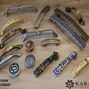 Pode incluir: Conjunto de ferragens decorativas para armários em vários estilos e acabamentos, incluindo ouro, prata e bronze. As ferragens incluem puxadores, botões e alças. O texto "FROM GERMANY" é visível no canto inferior esquerdo da imagem.