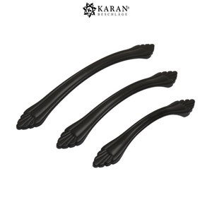 Op de afbeelding: Drie zwarte metalen kastgrepen met een decoratief, sierlijk ontwerp. De grepen zijn in verschillende maten.