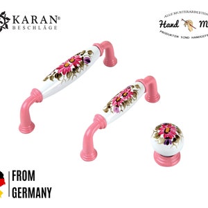 Peut inclure: Ensemble de trois boutons de cabinet en céramique rose avec des motifs floraux. Les boutons sont peints à la main avec des fleurs roses, blanches et violettes. Les boutons sont étiquetés "Hand Made".