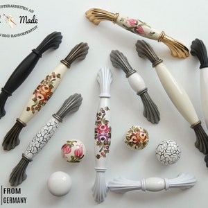 Könnte beinhalten: Sortiment an Keramik-Schubladengriffen mit floralen und geometrischen Designs. Die Griffe sind in verschiedenen Farben, darunter Weiß, Schwarz und Grau. Die Griffe haben ein dekoratives, verziertes Design.  Hand Made.  From Germany.