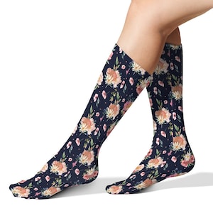 May include: A pair of knee-high socks with a floral pattern on a dark blue background. The flowers are pink, white, and yellow.