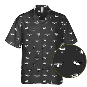 Puede incluir: Camisa negra de manga corta con un estampado de helicópteros blancos. La camisa tiene un cuello clásico y un corte regular. El diseño de helicópteros se repite por toda la camisa.