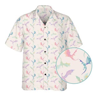 May include: A short-sleeved button-down shirt with a repeating pattern of pastel-colored dragons. The dragons are in shades of pink, blue, green, and purple on a cream-colored background. The shirt has a classic collar and black buttons.