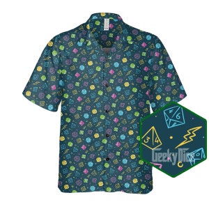 May include: A teal blue short-sleeved button-down shirt with a repeating pattern of dice and lightning bolts in yellow, pink, green, and blue. The shirt has a collar and a button-up front. The pattern is also shown in a close-up in the lower right corner of the image.