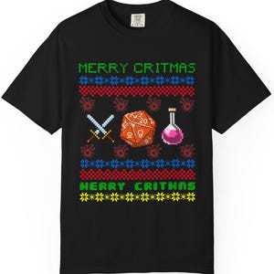 May include: Black t-shirt with a green, red, and yellow pixelated design that says "Merry Critmas". The design features a 20-sided die, two swords, and a potion bottle.
