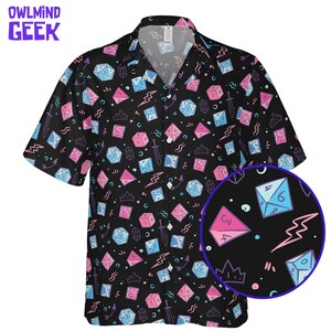 May include: Black short-sleeved shirt featuring a repeating pattern of dice, crowns, swords, and lightning bolts in pink and blue. The shirt has the text "OWLMINND GEEK" in purple at the top left.