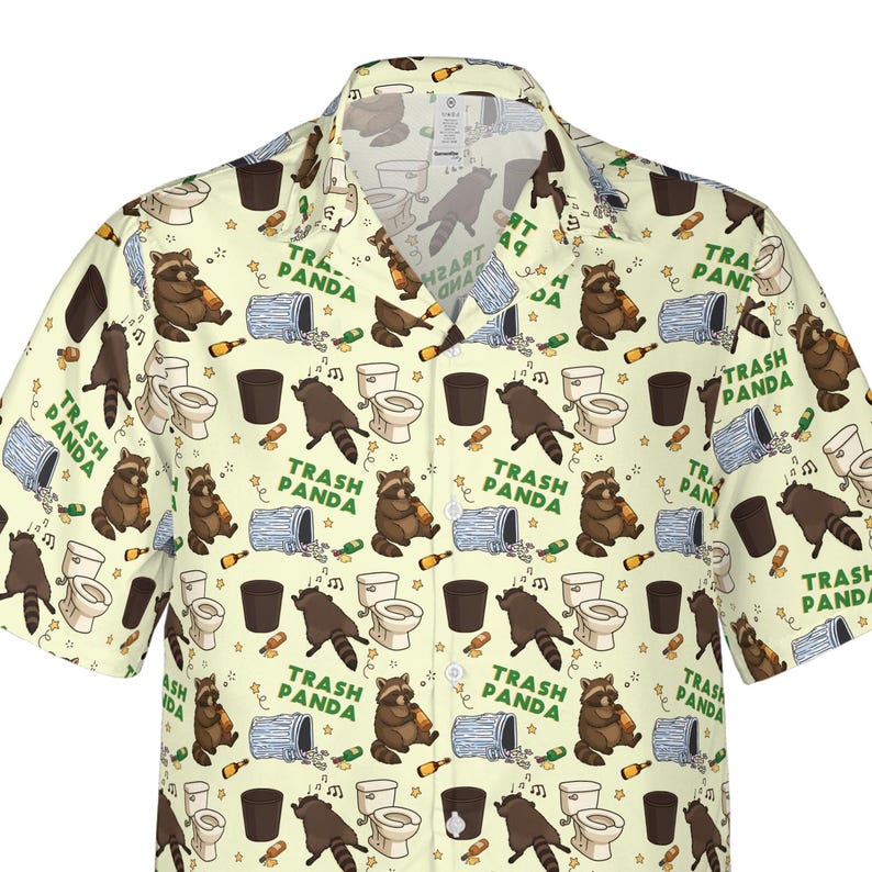 Pode incluir: Uma camisa de manga curta com bot&otilde;es em cor creme claro, apresentando uma estampa de guaxinins castanhos, sanitas brancas, caixotes do lixo azuis e garrafas castanhas. O texto "TRASH PANDA" est&aacute; impresso em verde por todo o padr&atilde;o.