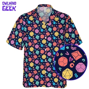 May include: Short-sleeved shirt with a navy blue background and a colourful dice pattern. The shirt features a collage of geometric shapes in various colours, including yellow, pink, orange, and teal. The text "OWLMINND GEEK" is in the upper left corner.