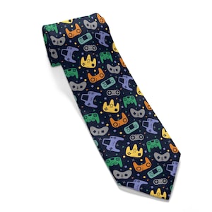 May include: A dark blue tie with a repeating pattern of colorful video game controllers. The controllers are in various shades of blue, green, yellow, and orange.