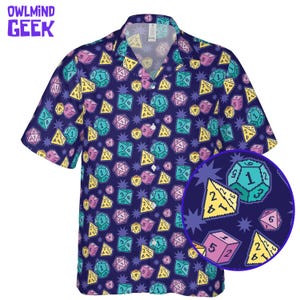 May include: A short-sleeved button-down shirt with a navy blue background and a colorful dice pattern. The dice are in various colors, including yellow, pink, and teal. The shirt has the text "OWLMINND GEEK" in purple.