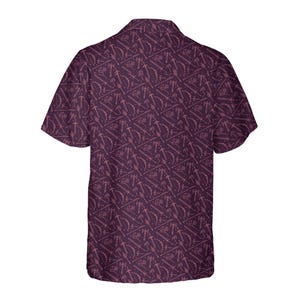 May include: A short-sleeved button-down shirt in a deep purple hue, featuring a repeating pattern of stylized weapons such as swords, axes, and bows. The shirt has a classic collar and a relaxed fit, suitable for casual wear.