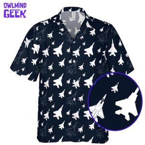 Peut inclure: Chemise bleu marine à manches courtes avec un motif d'avions de chasse blancs. La chemise a un col classique et une coupe régulière. Le texte "OWLMIN GEEK" est visible dans le coin supérieur gauche.