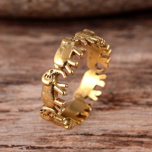 May include: A gold-toned ring featuring a design of elephants circling around the band.
