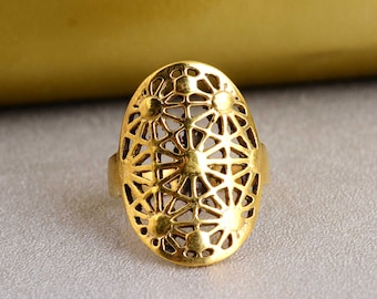 Puede incluir: Anillo de oro con un diseño delicado e intrincado que presenta un patrón circular de pequeños círculos y líneas. El anillo tiene forma ovalada y un acabado liso y pulido.