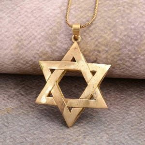 May include: A gold chain necklace with a large, gold, six-pointed star pendant.