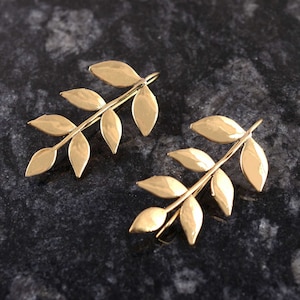 以下が含まれることがあります： 繊細な枝のデザインが施された、ゴールドリーフのイヤリングのペア。各イヤリングには、ずらりと並んだ5枚の葉が特徴です。