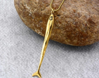 May include: A gold-toned fish pendant necklace with a textured surface. The pendant is attached to a gold chain.