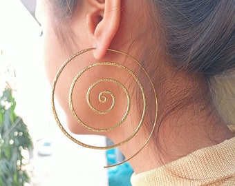 May include: Gold spiral hoop earrings with a textured finish. The earrings are large and have a circular shape.