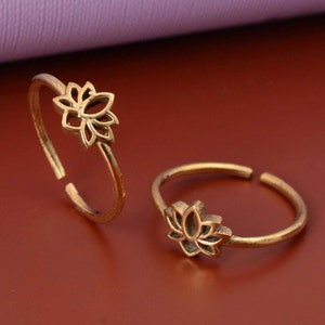Puede incluir: Dos anillos de dedo del pie de color dorado con un diseño de flor de loto. Los anillos son abiertos y ajustables.