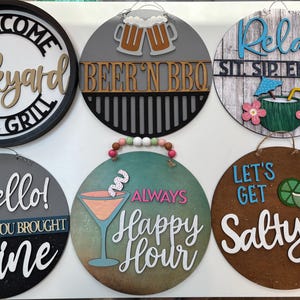 May include: Six circular wooden wall signs featuring various beverage and party themes. Designs include text like Welcome Backyard Bar & Grill, Beer 'N BBQ, Relax Sit Sip Enjoy, Hello Hope You Brought Wine, Always Happy Hour, and Let's Get Salty with graphics.