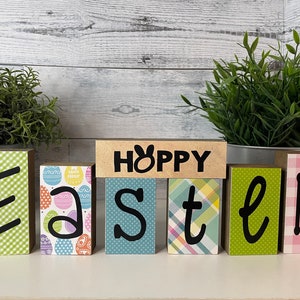 May include: Wooden blocks spelling "Happy Easter" with a bunny rabbit on the "Happy" block. The blocks are decorated with different patterns, including gingham, plaid, and Easter eggs.