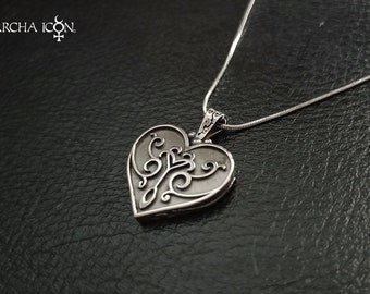 May include: A silver heart-shaped locket necklace with an intricate floral design. The locket is open and the chain is silver.