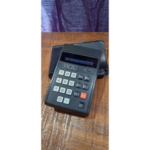 May include: A black calculator with a blue digital display. The calculator has the word "EXCEL" printed on it and has a standard layout of number keys, operation keys, and a clear key.