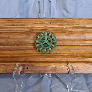 May include: A wooden shelf with three decorative knobs. The knobs are made of metal and have a green, blue, and red color scheme.