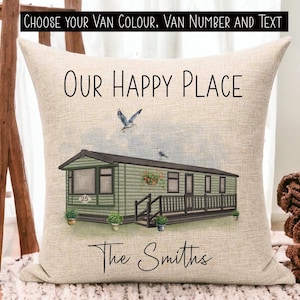 May include: A green and brown caravan with the text "OUR HAPPY PLACE" and "The Smiths" on a beige linen cushion. The caravan has a number "25" on the side.