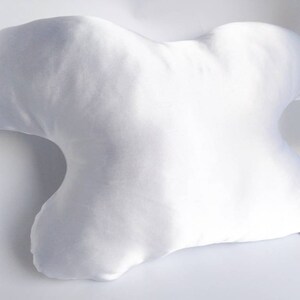 以下が含まれることがあります： 側面で寝るように設計された、ユニークな形をした白いサテンの枕。枕は柔らかく快適で、睡眠の質を向上させたい人に最適です。
