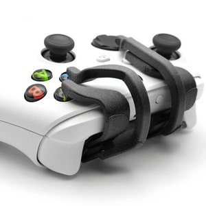 Op de afbeelding: Een witte Xbox-controller met een zwarte gripbevestiging. De grip is ontworpen om het comfort en de controle tijdens het gamen te verbeteren.