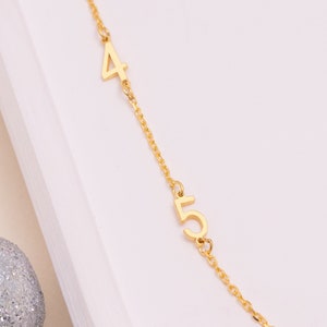 Sterling Silver Personalized Number Necklace next to a coin for scale, showing the dainty size of the pendant and chain. Ideal for minimalist jewelry.