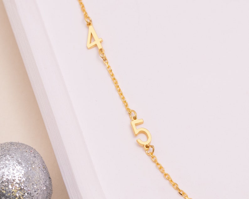 Sterling Silver Personalized Number Necklace next to a coin for scale, showing the dainty size of the pendant and chain. Ideal for minimalist jewelry.