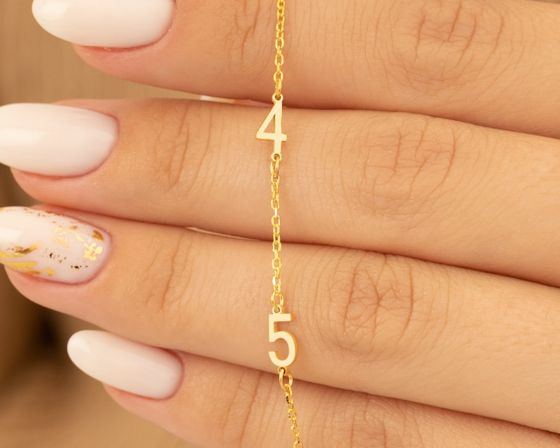 Hand gently holds a Rose Gold Plated Number Necklace, emphasizing its personal and delicate feel. Perfect for special cherished moments.