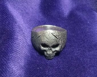 Può includere: Un anello in argento a forma di teschio con una superficie testurizzata. L'anello è progettato con un viso di teschio dettagliato.