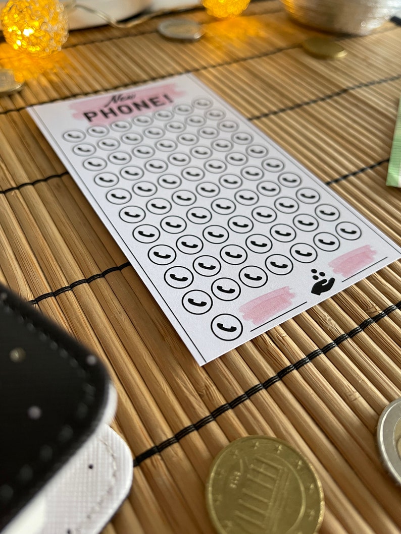 May include: A white card with the text "New Phone!" printed in black. The card has 50 black phone icons printed on it. The card is on a brown bamboo mat.