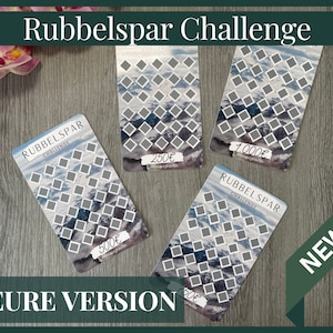 Könnte beinhalten: Vier graue und weiße Karten mit einer Bergszene und einem Quadratraster. Die Karten haben den Text "Rubbelspar Challenge" und verschiedene Geldbeträge: 500 €, 250 €, 1.000 € und 50 €. Die Karten liegen auf einer Holzoberfläche. Der Text "NEURE VERSION" befindet sich am unteren Rand des Bildes. Der Text "NEW" befindet sich in einem roten Rechteck in der oberen rechten Ecke des Bildes.