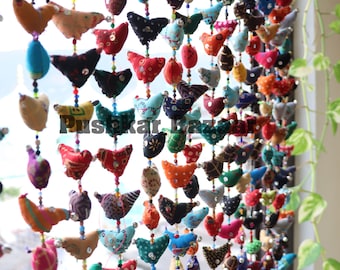 May include: A colorful string of fabric birds with beaded accents. The birds are in various patterns and colors, including red, blue, green, yellow, and purple. The string is hanging in front of a window.