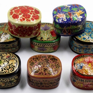 May include: Eight oval-shaped decorative boxes with intricate floral designs. The boxes are made of paper mache and are painted in various colors, including red, blue, green, black, and gold.
