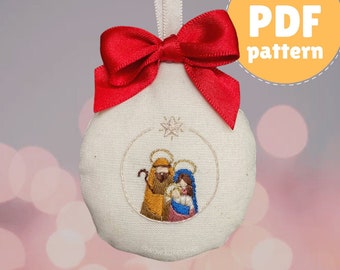 May include: A white fabric ornament with a red bow and an embroidered image of the Holy Family. The ornament is shaped like a sphere and has a loop for hanging. The image is surrounded by a circle and a star.
