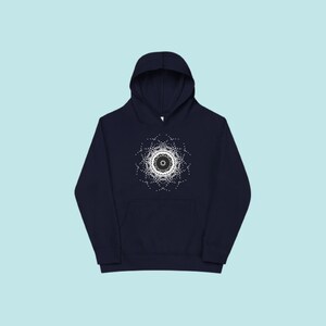 May include: Dark navy blue hoodie featuring a white and black circular pattern. The design is a detailed arrangement of dots and lines, forming a symmetrical, mandala-style image. The hoodie includes a front pocket and a hood.